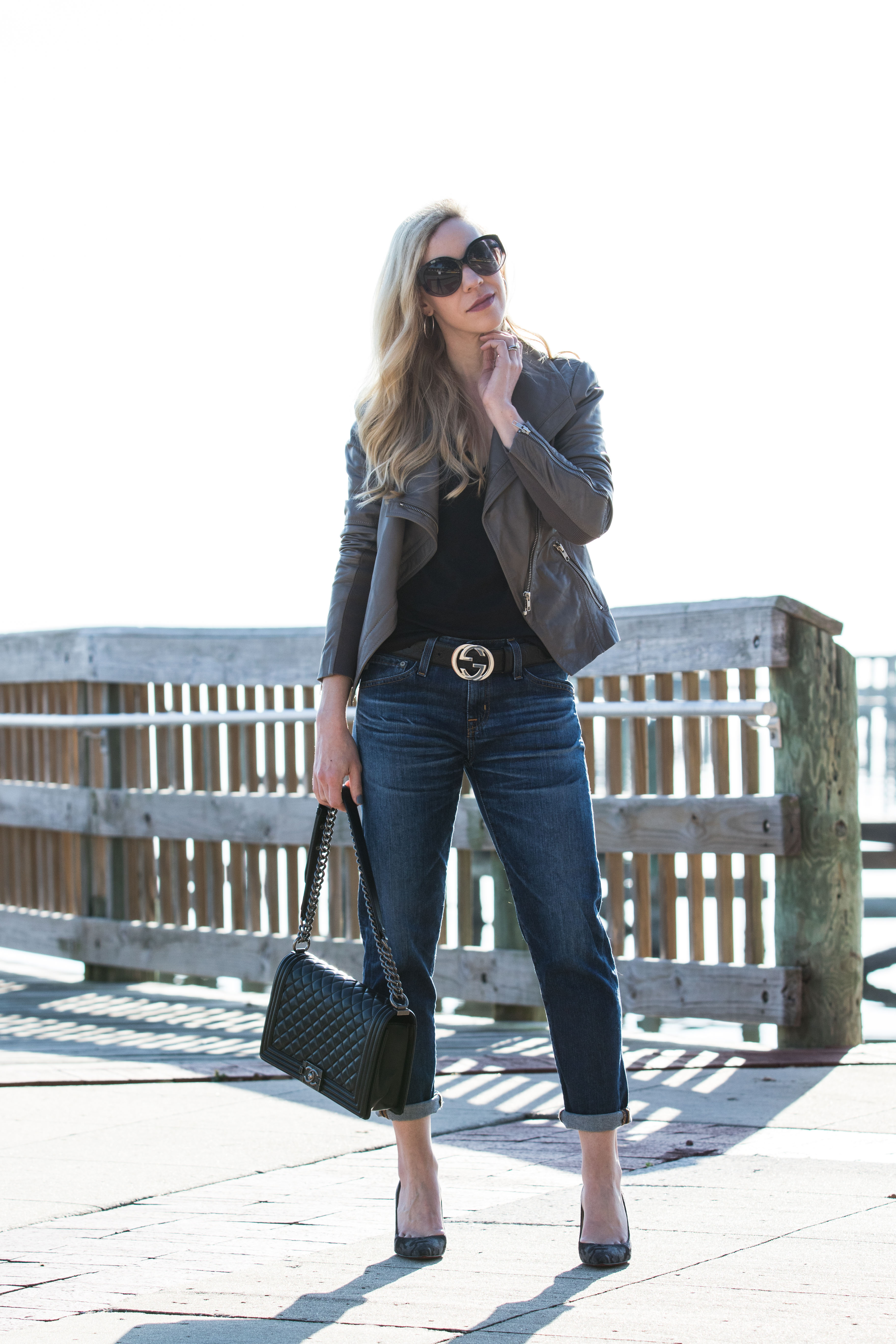 Meagan Brandon fashion blogger of Meagan's Moda wears Louis Vuitton black  shine shawl with leather moto jacket, gray high waist jeans and Marc Fisher  black Chelsea boots black and gray outfit 