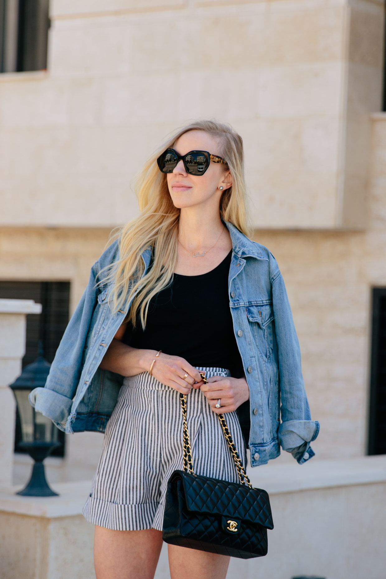 Meagan Brandon fashion blogger of Meagan's Moda styles high waist striped  shorts with Levi's denim jacket and Chanel classic flap bag, chic and casual  outfit with striped shorts for summer - Meagan's