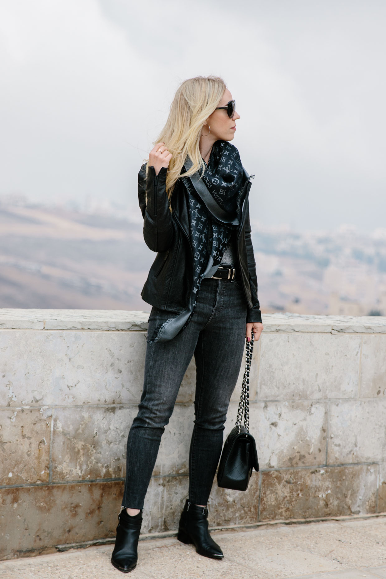 Meagan Brandon fashion blogger of Meagan's Moda wears Louis Vuitton black  shine shawl with black leather jacket, gray jeans and black moto boots for  chic black and gray outfit - Meagan's Moda