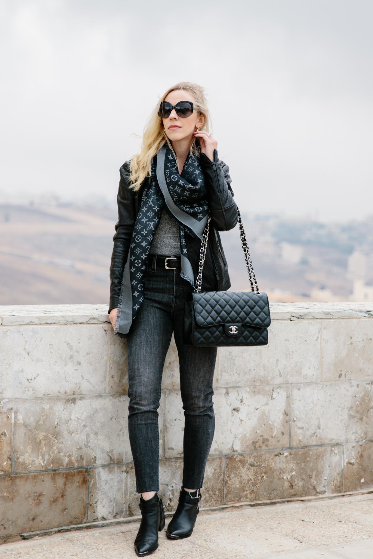 Meagan Brandon fashion blogger of Meagan's Moda wears Louis Vuitton black  shine shawl with black leather jacket, gray jeans and black moto boots for  chic black and gray outfit - Meagan's Moda