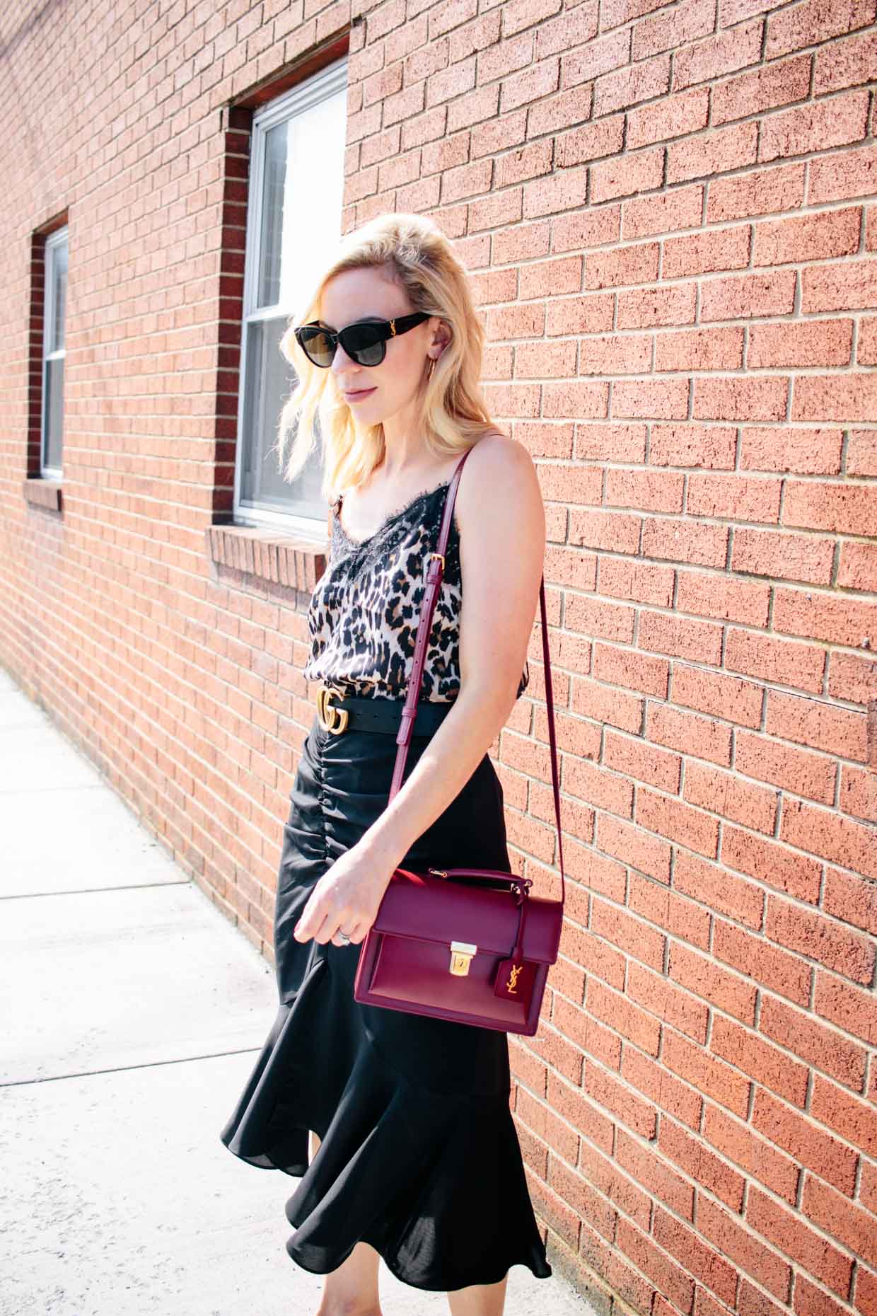 Meagan Brandon fashion blogger of Meagan's Moda shows leopard print  camisole outfit with black fluted midi skirt and red Saint Laurent high  school satchel - Meagan's Moda