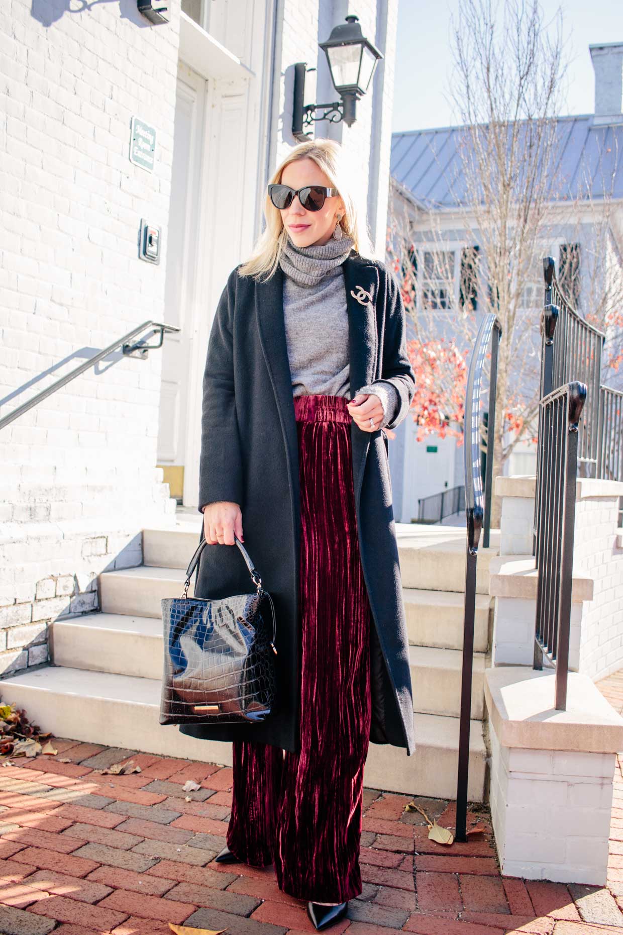 https://www.meagansmoda.com/wp-content/uploads/2019/12/Meagan-Brandon-fashion-blogger-of-Meagans-Moda-wears-Max-Mara-long-black-cashmere-coat-with-Chanel-brooch-and-red-velvet-wide-leg-pants-velvet-pants-holiday-outfit.jpg