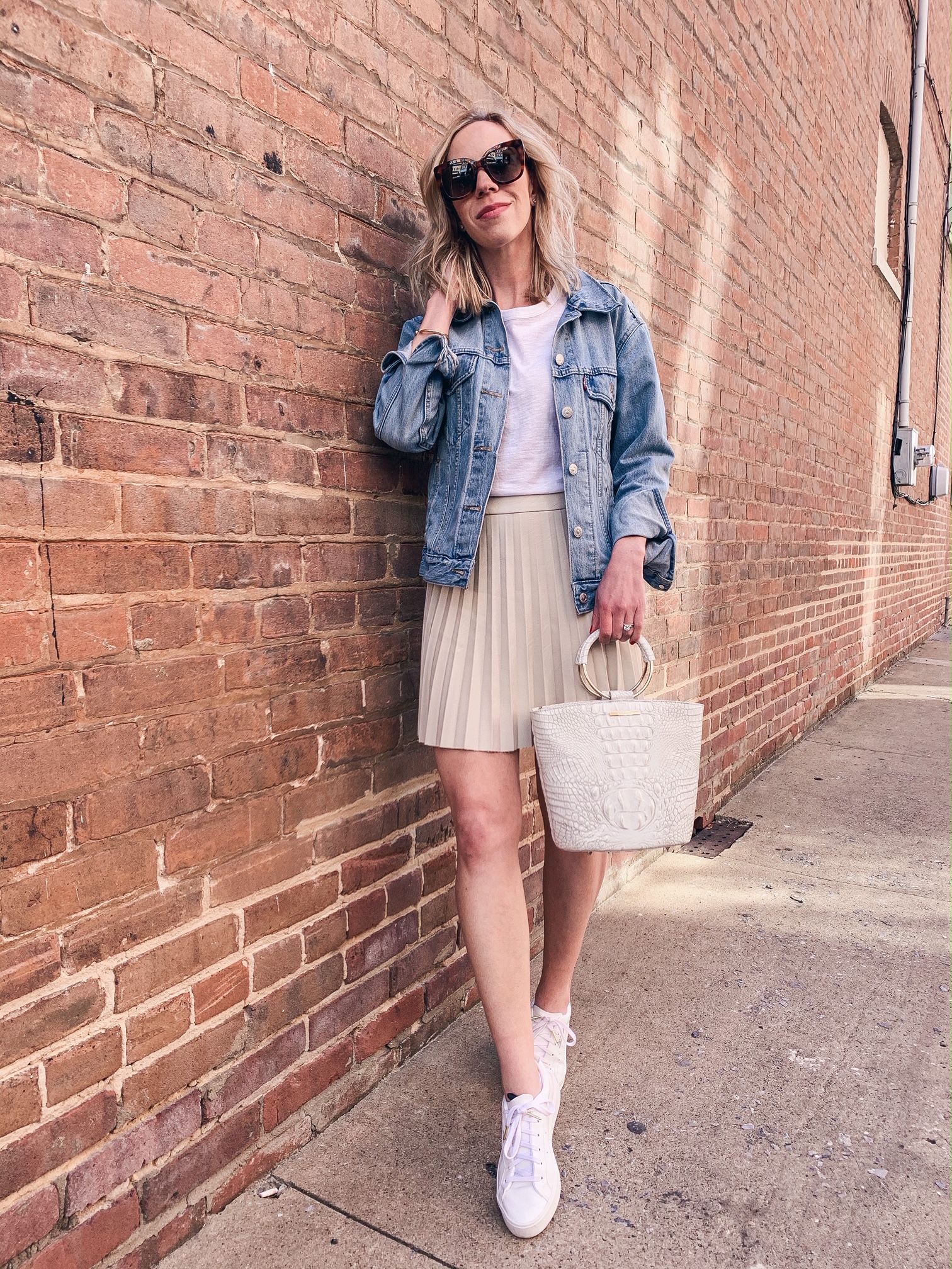 Meagan Brandon fashion blogger of Meagan's Moda shows how to style faux leather pleated skirt for spring with white sneakers