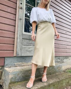 Meagan Brandon fashion blogger of Meagan's Moda wears white puff sleeve blouse with satin midi skirt and square toe sandals