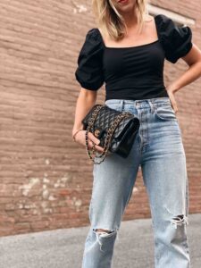 Meagan Brandon fashion blogger of Meagan's Moda wears black puff sleeve blouse with boyfriend jeans and Chanel classic flap bag black lambskin