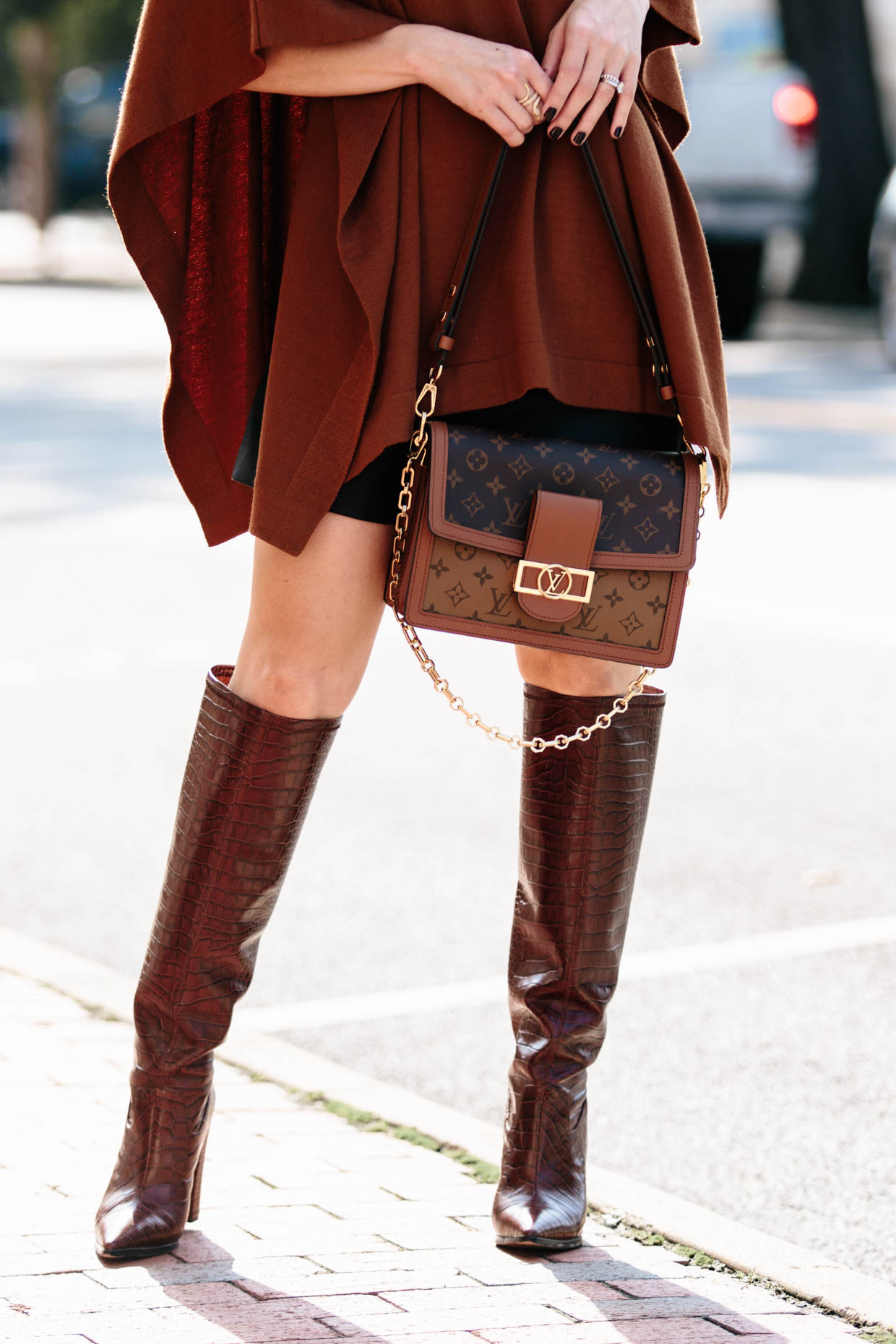 Meagan Brandon fashion blogger of Meagan's Moda wears rust colored poncho  with leather mini skirt, croc knee high boots and Louis Vuitton Dauphine -  Meagan's Moda