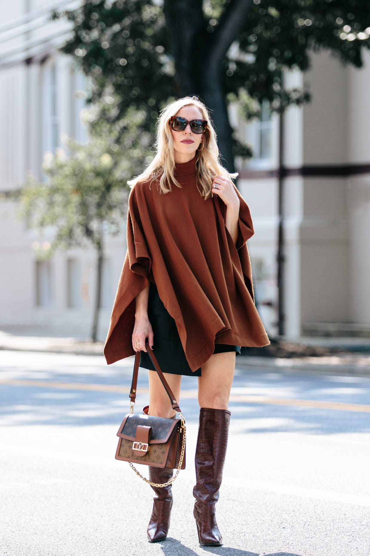 Meagan Brandon fashion blogger of Meagan's Moda wears camel poncho with black faux leather skirt, croc boots and Louis Vuitton Dauphine