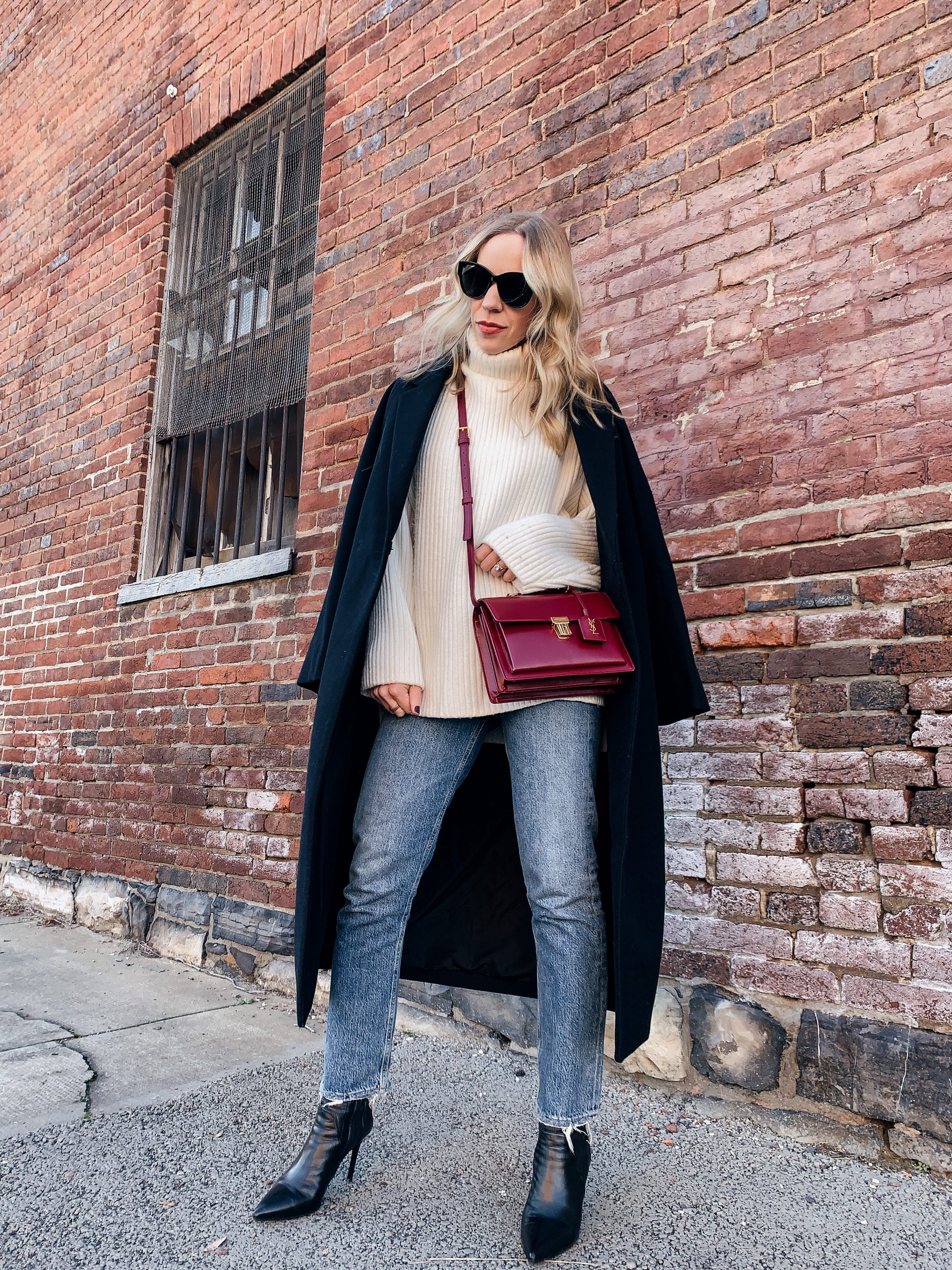 Meagan Brandon fashion blogger of Meagan's Moda wears black oversized coat with cream rib knit sweater, straight leg jeans and black leather sock boots