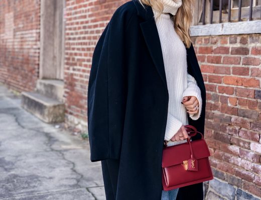 Meagan Brandon fashion blogger of Meagan's Moda wears oversized black wool coat over chunky cream sweater with red YSL bag