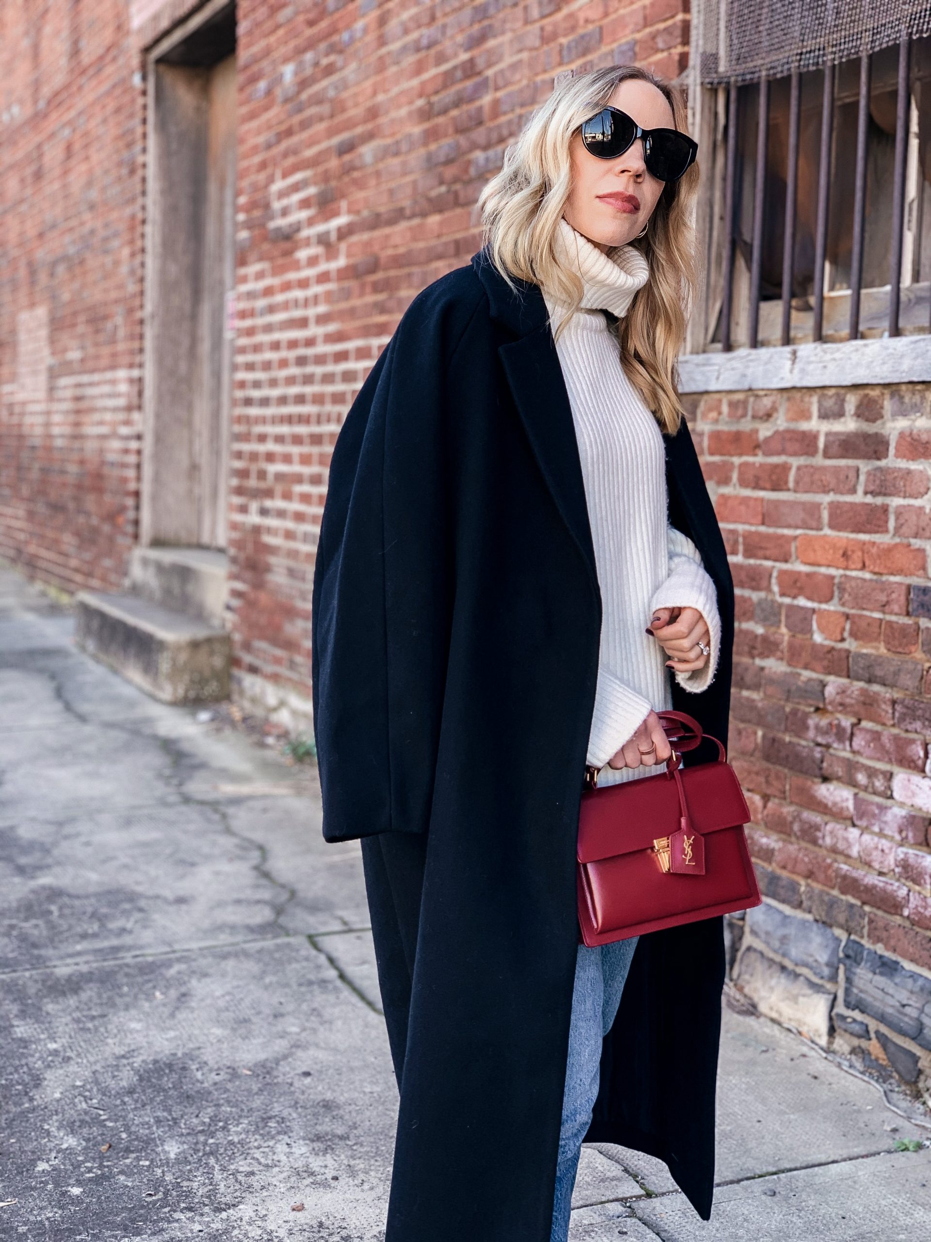 Meagan Brandon fashion blogger of Meagan's Moda wears oversized black wool coat over chunky cream sweater with red YSL bag