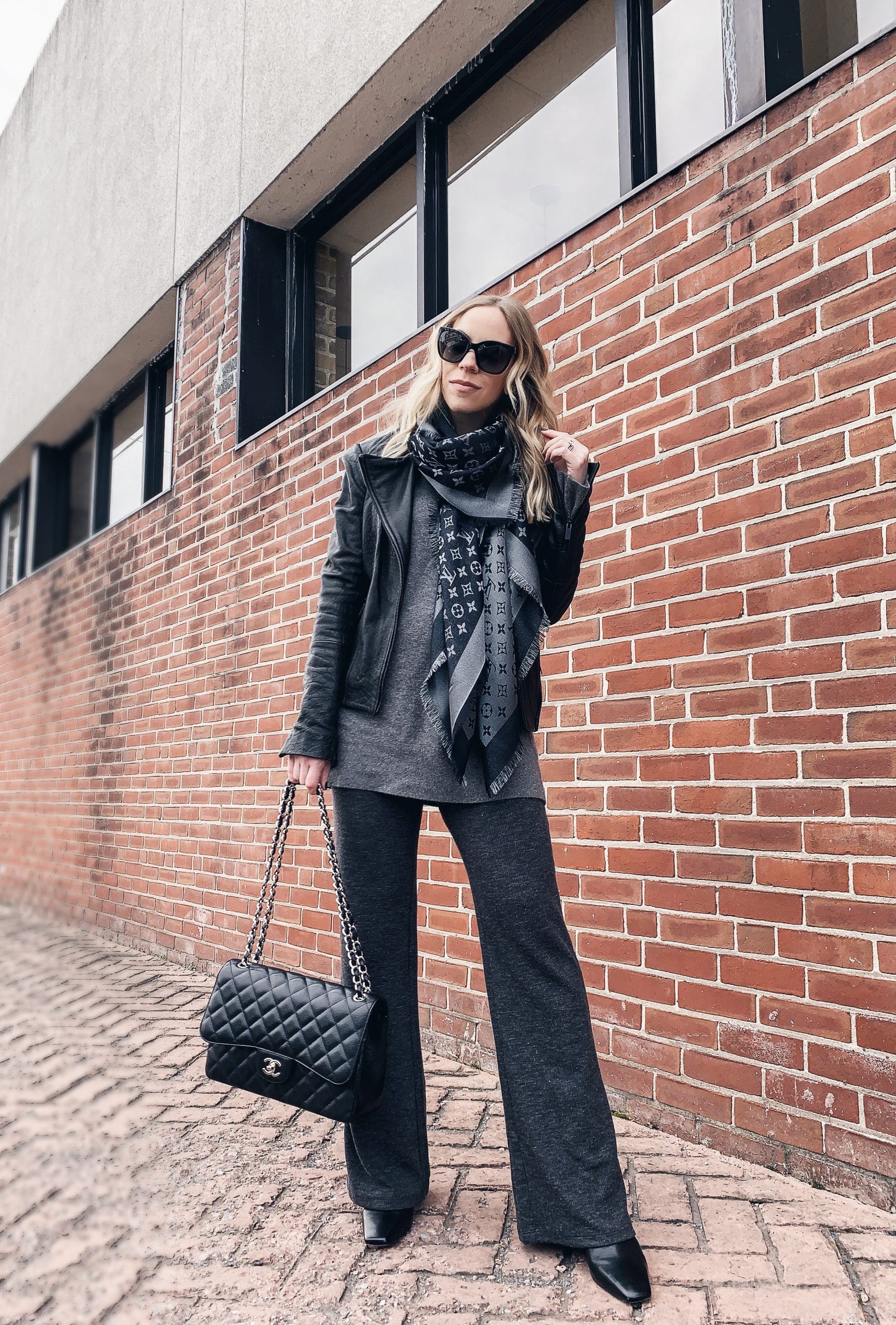 Meagan Brandon fashion blogger of Meagan's Moda wears Louis Vuitton black  shine shawl with leather moto jacket, gray high waist jeans and Marc Fisher  black Chelsea boots black and gray outfit 