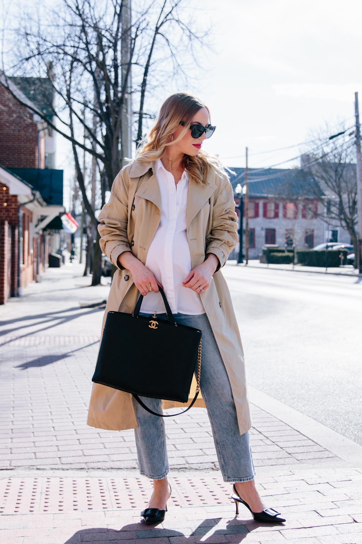 Meagan Brandon fashion blogger of Meagan's Moda wears khaki trench coat with white button shirt, straight leg cropped jeans and Chanel shopping tote spring outfit