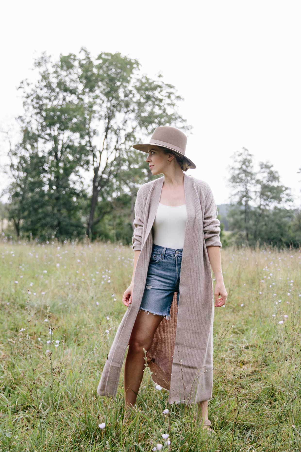 Meagan Brandon style influencer shows how to wear a duster cardigan for early fall with denim shorts and sandals