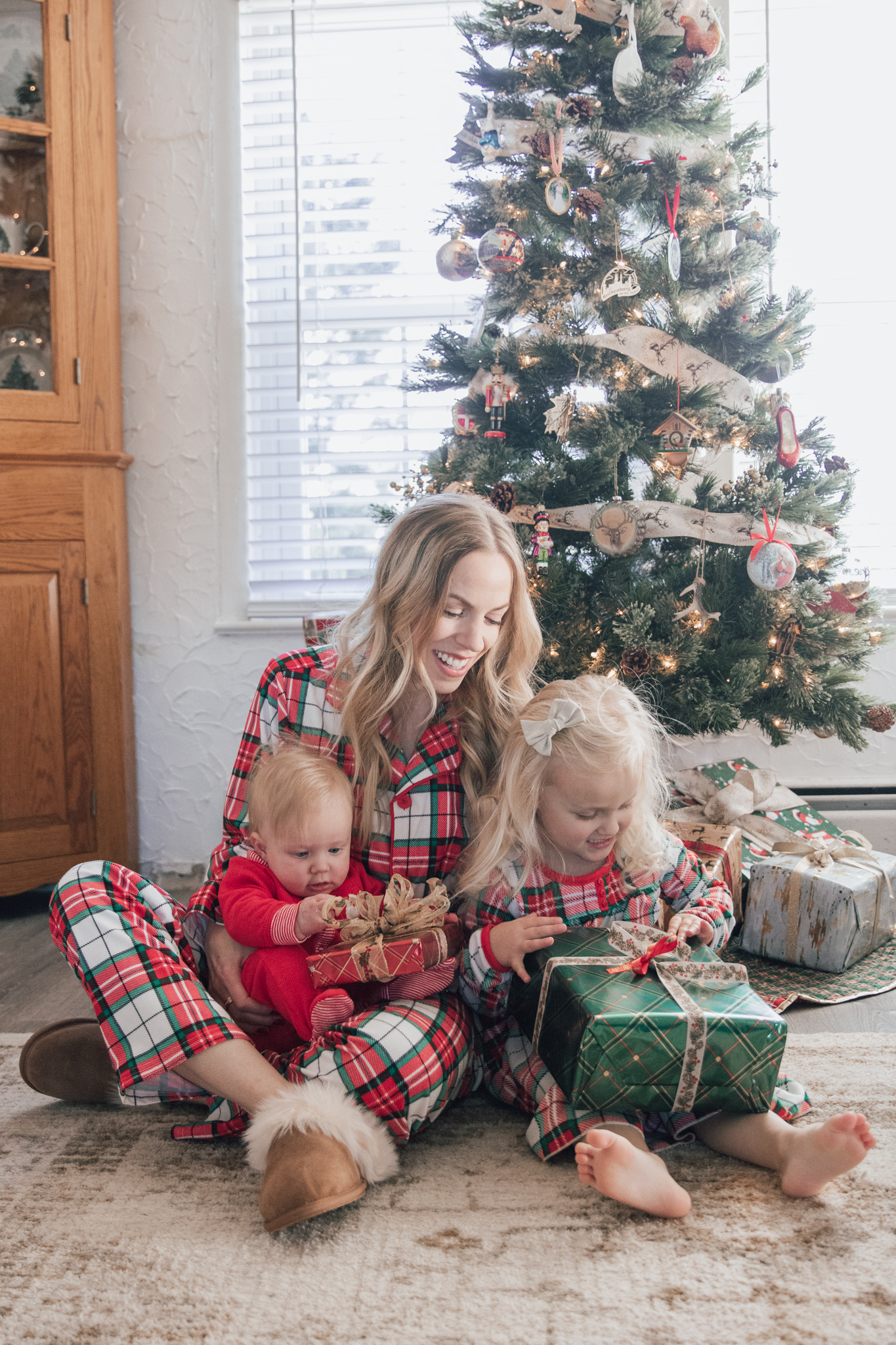 Meagan Brandon of Meagan's Moda wears matching plaid Christmas pajamas with toddler and baby girl