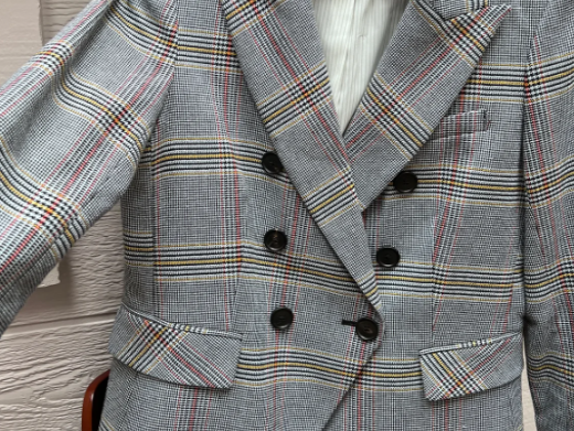 Pictured is a plaid gray red yellow and black blazer with black buttons and pocket flaps