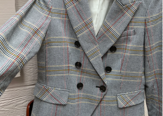 Pictured is a plaid gray red yellow and black blazer with black buttons and pocket flaps